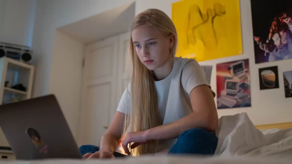 Junges Mädchen lächelt und nutzt Laptop – Persönliches 1:1 Mentalcoaching und individuelle Analyse zur Förderung mentaler Stärke im Leistungssport.