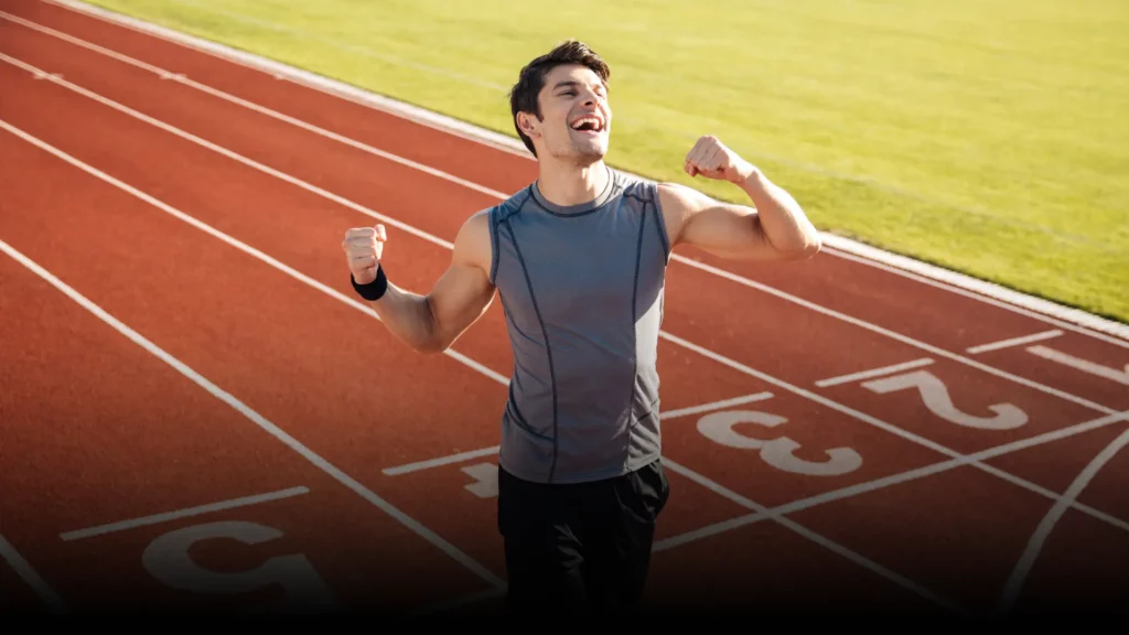 Läufer jubelt motiviert auf einer Laufbahn – Mentoring-Programm für Freizeitsportler zur mentalen Stärkung und Zielerreichung.